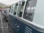Photo shows the side of a VW 13-window deluxe bus painted sea blue on the lower half